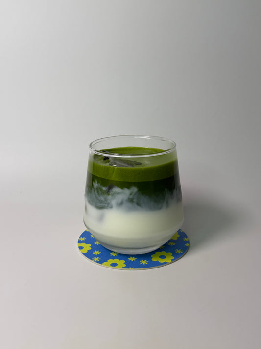 Two-layered drink in a glass with green and white layers on a white background
