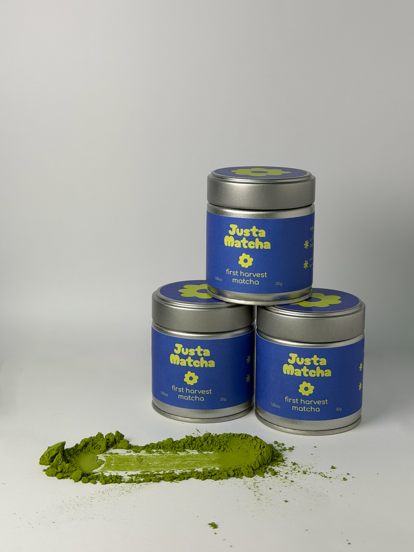 Three tins of Justa Matcha green tea powder on a white background